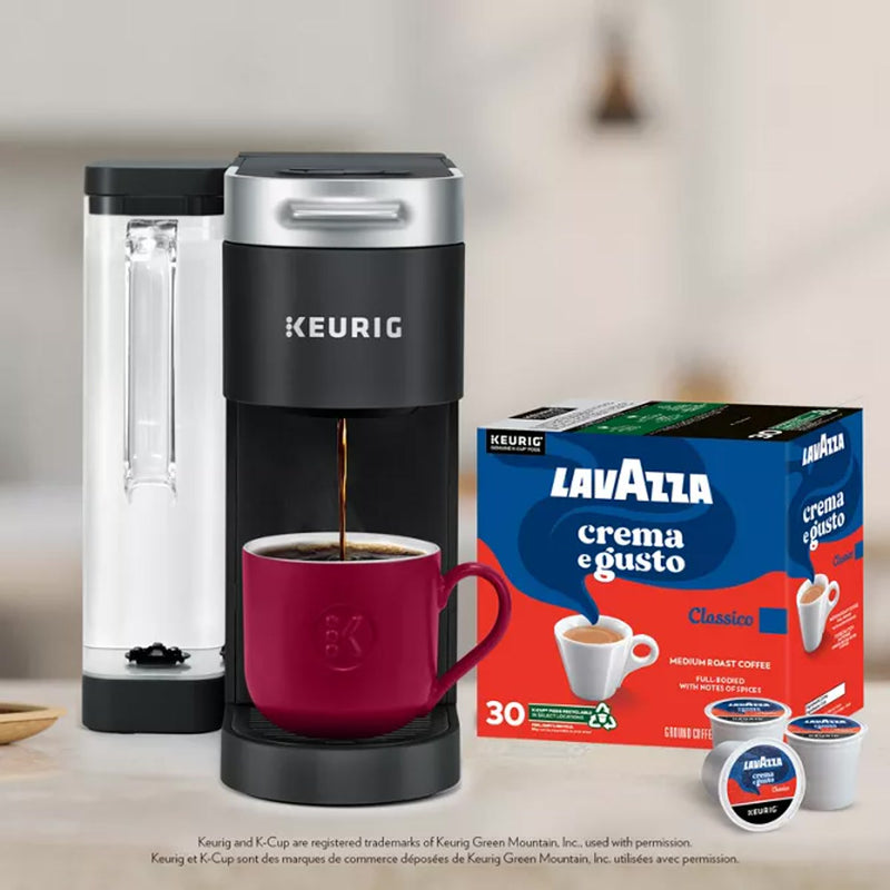 A Keurig brews rich coffee into a red mug with Lavazza Crema e Gusto K-Cup® Pods (Box of 24) beside it, proudly showcasing the brand's commitment to sustainability and delicious, medium roast flavor in each cup.