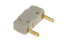 Close-up image of the DeLonghi Parts Mini Switch (model 5132104100) with a white plastic housing and two gold-colored metal prongs extending from one side. This switch is compatible with Primadonna and Magnifica models, featuring two holes on the top surface for secure installation.