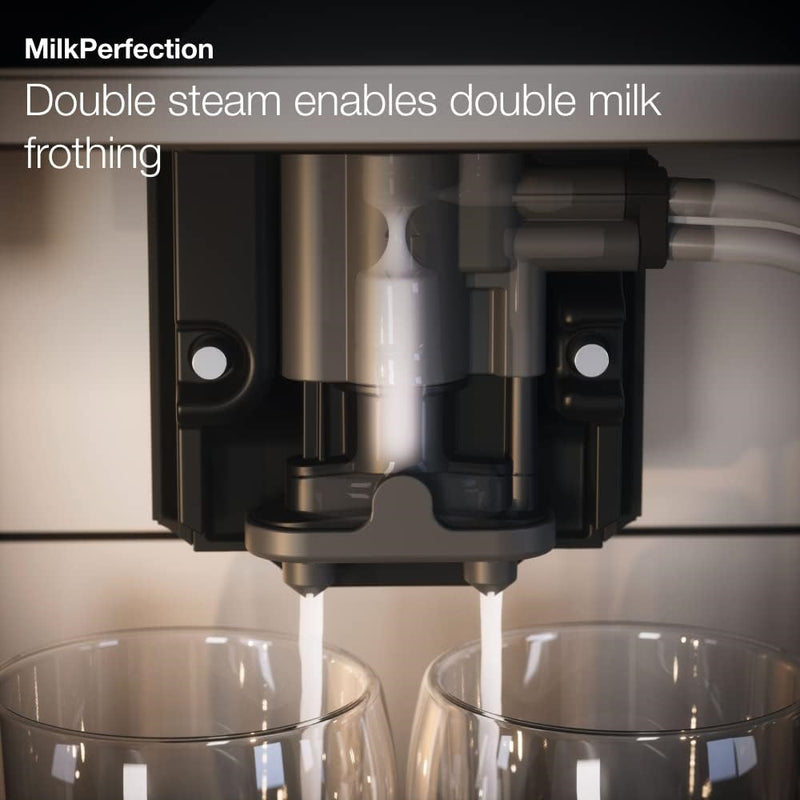 Close-up of the Miele CM6160 Milk Perfection Countertop Coffee Machine (Lotus White) dispensing frothed milk into two glass cups. Text at the top-left corner reads, "Miele MilkPerfection - Double steam enables double milk frothing." The setup suggests a feature that offers simultaneous milk frothing for two beverages with OneTouch for Two functionality.