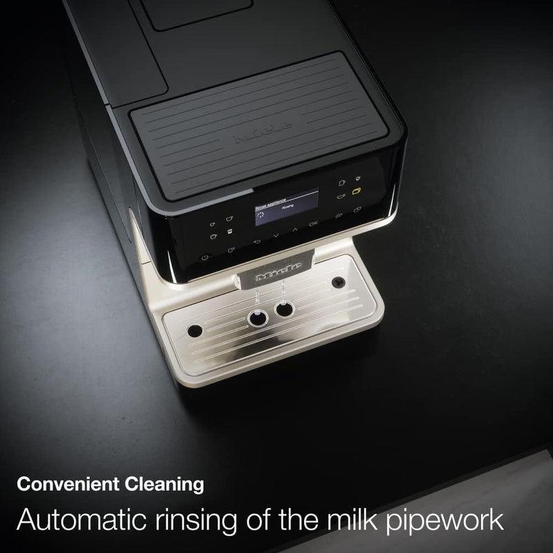 Image showing a sleek, white Miele CM6160 Milk Perfection Countertop Coffee Machine on a dark surface. The machine features a digital display and touch controls, offering one-touch programming. Text at the bottom reads, "Convenient Cleaning - Automatic rinsing of the milk pipework.