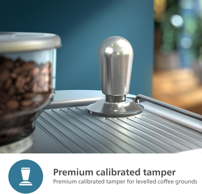 A Philips Barista Brew Semi Automatic Espresso Machine PSA3218/01 in sleek silver is placed on a metallic surface next to a dual bean container filled with assorted coffee varieties. The background is blurred, putting the focus on the espresso machine in the foreground. Text at the bottom reads, "Premium calibrated tamper for levelled coffee grounds.