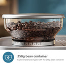 A close-up of a transparent 250g bean container filled with coffee beans, showing measurement markings. The container is part of the Philips Barista Brew Semi Automatic Espresso Machine PSA3218/01 (Silver), equipped with a dual bean container. Below the image, text reads "250g bean container - Explore new bean types with the 250g bean container from Philips.