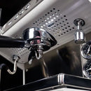 Close-up of the Conti ACE Espresso Machine in black highlights a portafilter secured in position and a dual pressure gauge. Its multi boiler system guarantees precise coffee brewing, while the stainless steel finish reflects light, underscoring the machine's sleek design.