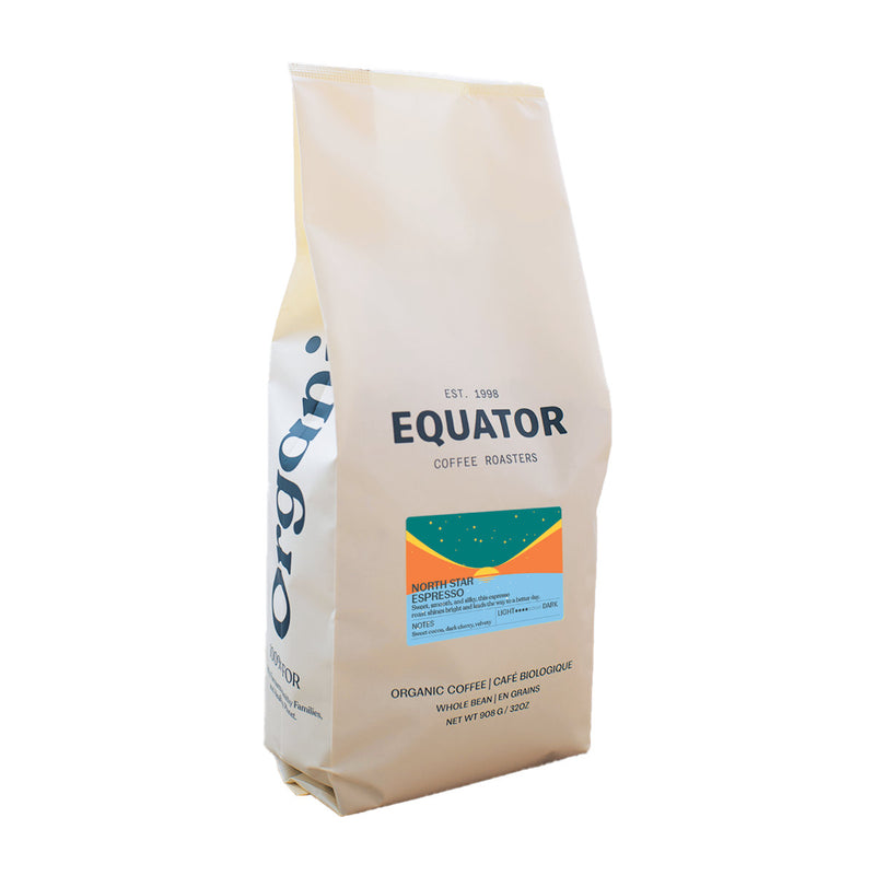 A beige bag of Equator Coffee Roasters North Star Coffee Bean (908g/2lb) features a medium-dark roast blend. The blue and orange label highlights its rich, organic heritage with origin details and tasting notes prominently displayed.