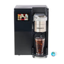 The Keurig K3550 K-Cup® Commercial Brewing System showcases a sleek black and silver design with a touchscreen displaying a fresh coffee. Perfect for workplaces, it stands ready with iced coffee beneath the dispenser and a single pod nearby.