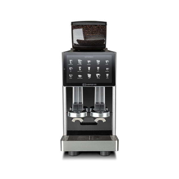 The Eversys Shotmaster 2 Group Head Coffee Compact Classic Espresso Machine c/Classic (Tempest) by Eversys is a sleek, modern espresso machine featuring a digital touch screen display showcasing various drink options. This fully automatic machine, perfect for high volume environments, includes a bean hopper at the top and dual coffee dispensers underneath. Its clean design is accentuated by a sophisticated metallic and black color scheme.