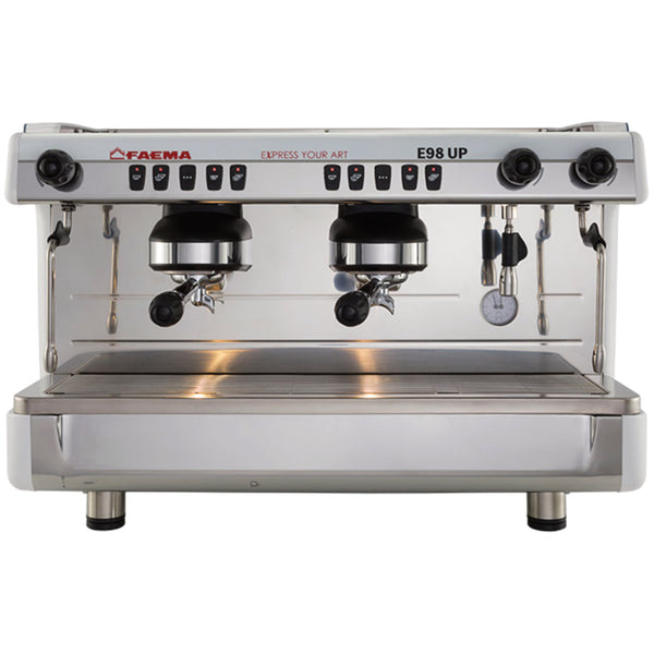 The Faema E98UP 2 Group Head Espresso Machine F01-UL210VWTB999A (White) by FAEMA is a stainless steel commercial espresso machine with an ergonomic and robust design. It features two group heads, steam wands on both sides, a hot water dispenser, and a drip tray at the bottom. The machine is labeled "FAEMA E98 UP" and includes various buttons and knobs for controls.