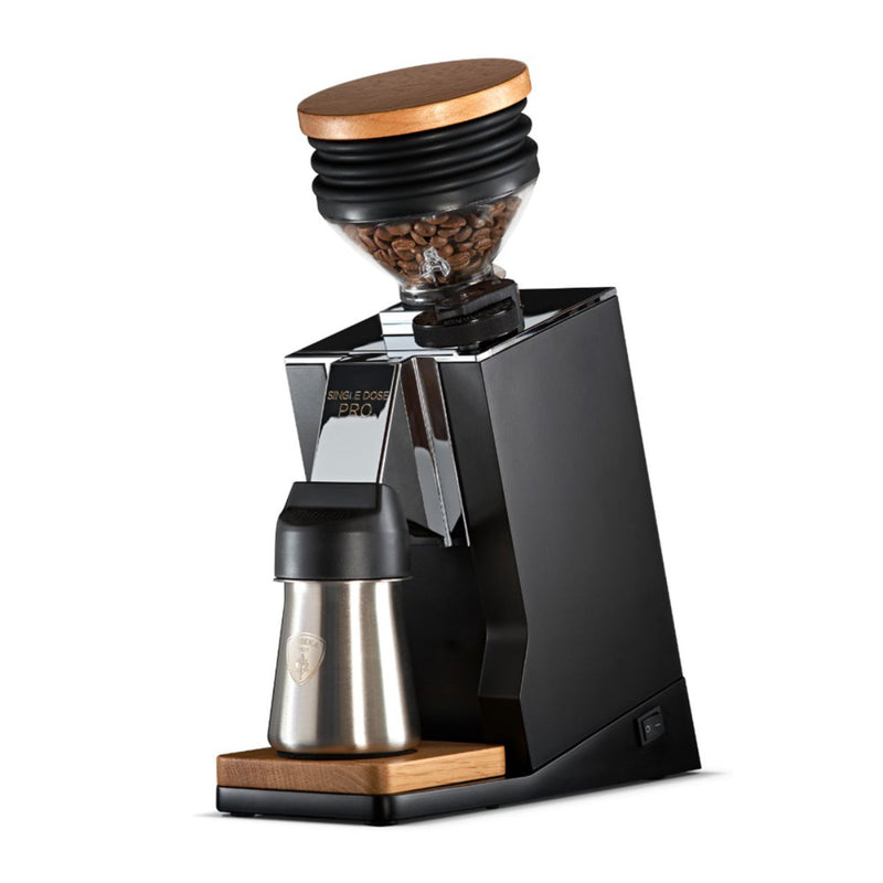 The Eureka Oro Mignon Single Dose Pro Grinder by Eureka features a sleek black design with flat burrs, a stainless steel container, wooden accents, and a transparent top filled with coffee beans. Its modern and compact construction ensures zero-retention for a perfect brew every time.