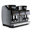 The Eversys Shotmaster 4 Group Head Milk System Pro Super Traditional Espresso Machine ms-pro/ST (Charcoal) features a sleek metallic finish with multiple dispensing nozzles, dual touchscreen interfaces, and large coffee bean hoppers on top. Branded "Eversys," it includes a built-in milk module and steam wand with Everfoam, making it ideal for high-volume coffee preparation in professional settings.