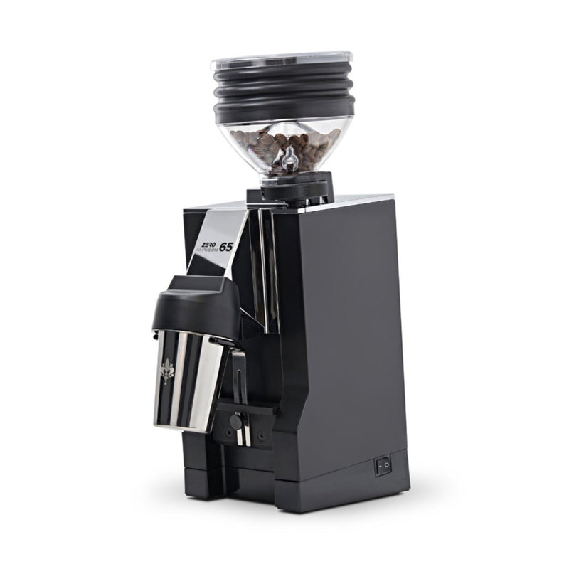 The Eureka Mignon Zero 65 All Purpose Grinder, in black, features a sleek design with a transparent hopper brimming with coffee beans. Its modern styling includes a stainless steel spout and zero-retention grind chamber to dispense freshly ground coffee with minimal waste.