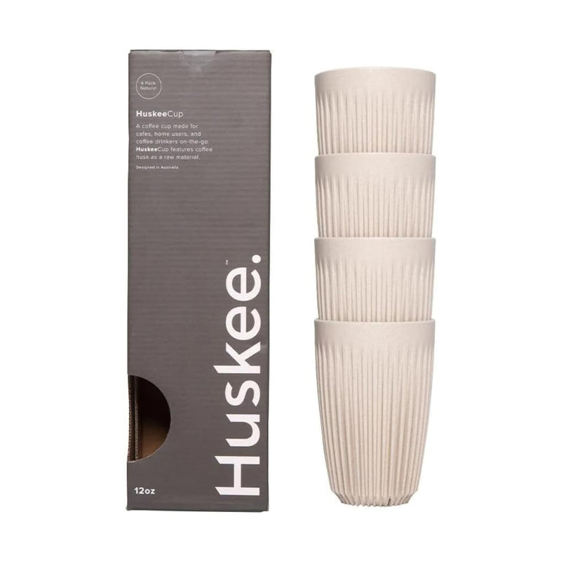 A stack of four Huskee HUSKEE Cup 12 oz/355ml reusable coffee cups in natural beige, featuring a ribbed design, is displayed next to a grey rectangular box labeled "Huskee" and containing product details. The sustainable coffee husk cups are positioned vertically, while the box stands upright on the left side of the image.