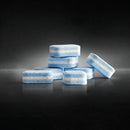 A collection of Miele UltraTabs All in 1 Dishwasher Cleaning Tablets from the box of 60 is stacked against a dark background. These tablets, featuring blue and white stripes, have a smooth, glossy surface and are arranged in a slightly scattered manner with some lying flat and others standing on their sides.