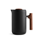 The Fellow Clara French Press (Matte Black + Walnut) by Fellow is a minimalist coffee or tea pot with a sleek design, featuring a smooth matte finish. It has a cylindrical shape with a wooden lid and matching wooden handle, offering barista-level functionality. This elegant French Press rests on a flat surface against a plain white background.