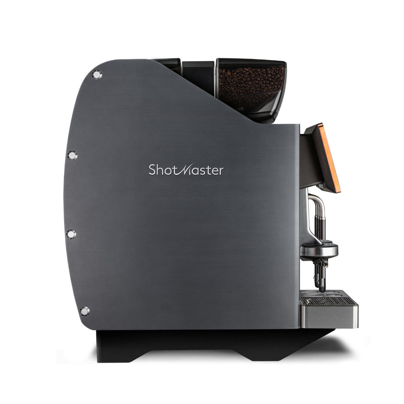 A side view of the charcoal Eversys Shotmaster 2 Group Head Steam Wand Super Traditional Espresso Machine s/ST. It features a clear panel on top for coffee beans, a built-in grinder, and a spout over the drip tray for dispensing coffee. The sleek and modern design by Eversys ensures high volume espresso production with consistent extraction.