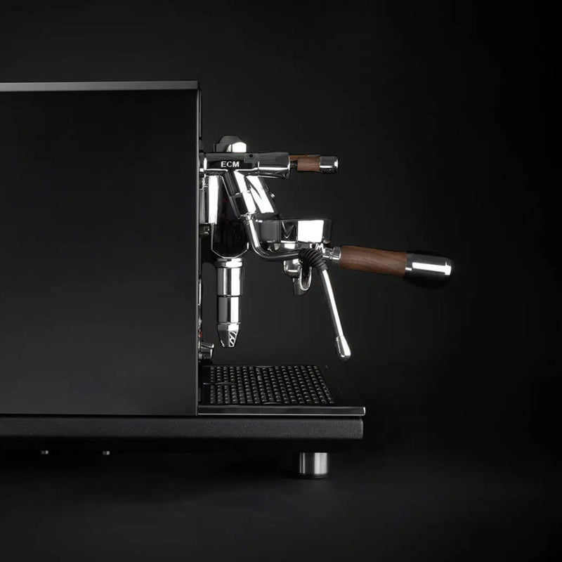 A special edition ECM Synchronika Espresso Machine - Dual Boiler with PID in black is shown against a black background. This sleek espresso machine features wooden handles and a portafilter with the E61 Group Head. The brand name "ECM" is visible on the front, showcasing its modern and minimalist design.