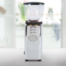 The ECM C-Manuale 54 Burr Grinder by ECM, made of stainless steel, is perfect for freshly ground beans with its transparent hopper. It sits on a light-colored countertop, showcasing its straightforward design in a softly blurred kitchen background.