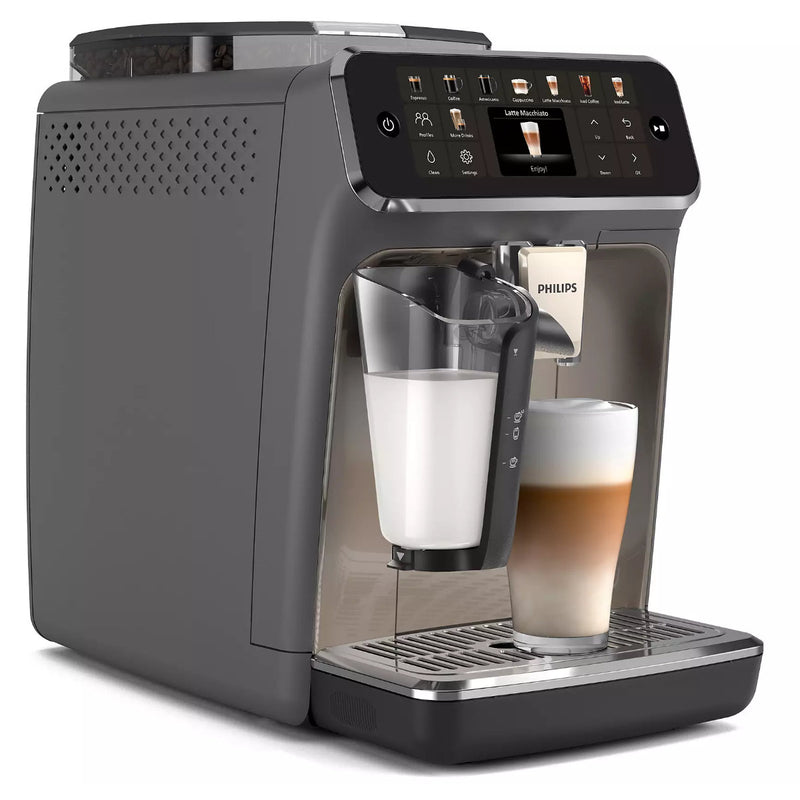 The Philips 5500 LatteGo Super Automatic Espresso, Cappuccino, & Latte Machine with SilentBrew EP5544/90 is a sleek, modern coffee machine featuring a digital touchscreen interface. This stylish device brews layered cappuccinos with its SilentBrew technology ensuring quiet operation while frothing milk into a transparent glass cup. The exterior boasts a primarily gray color with a metallic finish and prominently displays the Philips logo.