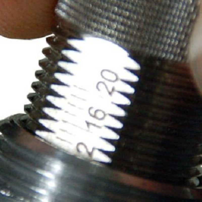 Close-up of the detailed metal threads on a cylindrical object, with engraved numbers "16" and "20" partially visible on its shining surface. A person's finger and hand grip the JoeFrex Technic Calibrated Dynamometric Adjustable Tamper Handle (Gunmetal), showcasing JoeFrex tamper grip technology. The image highlights the intricate threading and precise engraved markings.