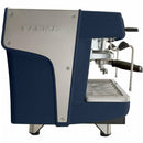 Side view of the Faema Prestige Plus 2 Group Head Tall Cup Autosteam Espresso Machine F01-UQ210T2BTDDGA (Indigo Blue) by FAEMA, showcasing its sleek, modern design with a combination of indigo blue and stainless steel panels. It features a portafilter, steam wand, and an advanced thermal system for adjustable temperature control. The machine is mounted on short, sturdy legs.