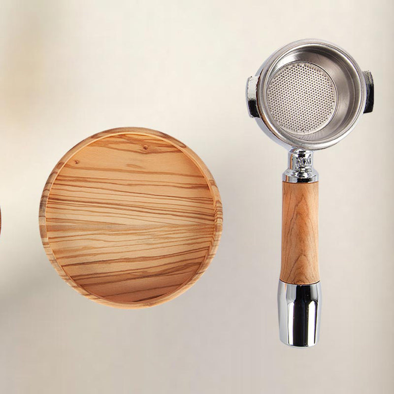 A top-down view of the ECM Puristika Semi Automatic Espresso Machine, complemented by a wooden coffee tamper base and portafilter with a wooden handle, is elegantly displayed on a light background, hinting at the presence of an E61 group head for the perfect espresso shot.