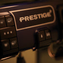 Close-up of a control panel featuring the brand name "FAEMA." The panel includes various buttons with icons, possibly indicating settings or functions. The lighting is dim, highlighting the central part of the Faema Prestige Plus 2 Group Head Tall Cup Autosteam Espresso Machine (Indigo Blue) and emphasizing its professional thermal system and adjustable temperature features.