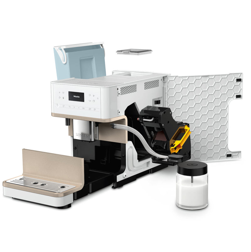 The image displays an open, disassembled Miele CM6360 Super Automatic Countertop Coffee & Espresso Machine in Lotus White with various internal components and external parts laid out, including a milk container. The main body features a digital display and a brewing mechanism, exposing the inner machinery and wiring.