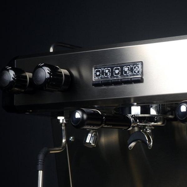 A close-up of the Conti CC100 1 Group Espresso Machine in black, featuring a digital display and control knobs. The sleek stainless steel surface enhances coffee extraction, beautifully set against a dark background.