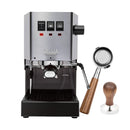 A Gaggia Classic E24 Espresso Machine RI9380/46 in stainless steel, featuring a bottomless walnut portafilter and a matching walnut tamper set beside it. The machine is equipped with three sleek buttons and proudly carries the trusted Gaggia brand, making it perfect for crafting your ideal espresso shot.