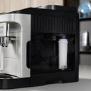 A close-up of a sleek, modern coffee machine featuring the DeLonghi Water Filter for ECAM Type Espresso Machines (DLSC002) in the transparent side compartment. The black and silver design sits effortlessly on a white countertop, ensuring your drinks improve beverage quality while reducing limescale buildup. Blurred kitchen items enhance the background.