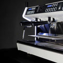 Introducing the Conti MC Ultima Espresso Machine in Black—a modern, sleek appliance featuring dual spouts and LED backlighting. Its design includes rows of buttons and digital displays set against a dark background, emphasizing its shiny metal finish and minimalist aesthetics. Equipped with pre-infusion technology and adjustable temperature settings, it provides a customized brewing experience.