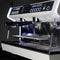 The Conti MC Ultima Espresso Machine in black, featuring dual dispensers and digital controls, stands out against a dark background. It showcases shiny metal components, programmable doses, adjustable temperature settings, and a spacious tray for cups.