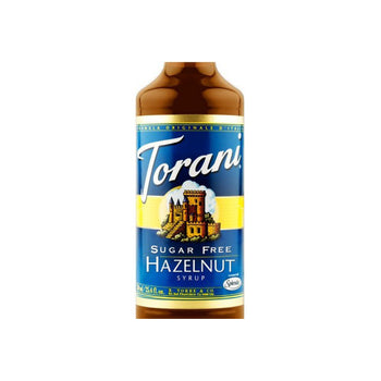 A bottle of Torani Syrup Sugar Free Classic Hazelnut. The label is blue and yellow, adorned with an image of a castle and mountains. "Torani" graces the top while "Sugar-Free Classic Hazelnut" is at the bottom. The bottle features a gold cap for an elegant touch.