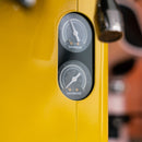 Close-up of a yellow Sanremo Cube R Heat Exchanger Espresso Machine E61 Group Head featuring two analog gauges. The upper gauge displays measurements from 0 to 2.5 bar, while the lower gauge ranges from 0 to 250 PSI, indicating pressure settings. Part of the smart espresso machine's handle is visible.