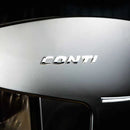 Close-up of a shiny surface with the word "Conti" embossed in metallic letters on the Conti X-One Espresso Machine (Black). The background is dark, highlighting the smooth texture and reflective quality, enhanced by advanced technology that seamlessly integrates an electronic temperature adjustment feature for precision control.