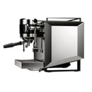 Introducing the Rocket Bicocca Dual Boiler Espresso Machine RE602V3B11 in black, a stylish piece that embodies Italian heritage with its sleek stainless steel finish and modern angular design. This machine features an ergonomic layout with a portafilter handle, steam wand, and drip tray, all beautifully set against a white backdrop. Available for preorder from Rocket.