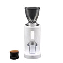 A sleek, modern DF Grinders DF83 ELR Single Dose Coffee Grinder with a white base and transparent hopper on top. Below the ultra-low retention hopper, there's a grounds container featuring 83mm DLC burrs. To the left is a small black tamper with a wooden top. Both items are set against a pristine white background.