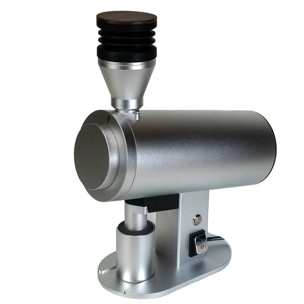 The DF Grinders DF83V is a metallic silver, cylindrical coffee grinder with a black and silver top, mounted on a sturdy base. It has 83mm DLC burrs and operational buttons for barista-level consistency in scientific or industrial settings.