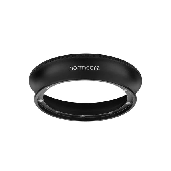 The Normcore 58mm Dosing Funnel is a black, circular coffee distribution tool featuring a flat top with textured edges for grip and the brand name "normcore" in white text. Its hollow design ensures even coffee grounds distribution. This Normcore accessory also doubles as a magnetic dosing funnel with neodymium magnets for secure attachment.