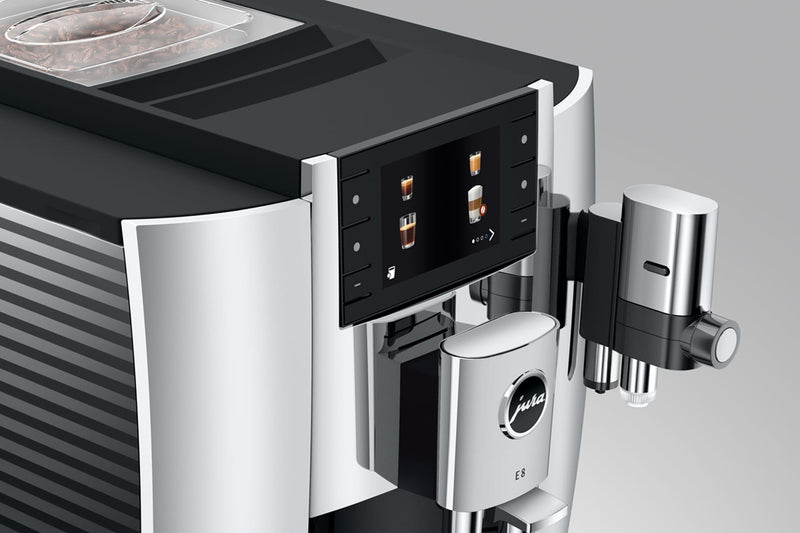 The Jura E8 Chrome Automatic Coffee Machine 15646 (Latest Version) is a sleek appliance in a stylish chrome finish with a touch screen display that offers various coffee options including espresso and cappuccino. Featuring two dispensers and a compartment for coffee beans on top, this machine delivers barista-quality coffee effortlessly.