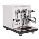 The ECM Synchronika Espresso Machine - Dual Boiler with PID and Flow Control (Special Edition White) by ECM features dual spouts, multiple gauges, and various levers. It includes a stainless steel drip tray at the front and is set on a black base with metal legs. This model is equipped with dual boilers and an E61 Group Head, along with two indicator lights, one red and one green, positioned on the lower left side.