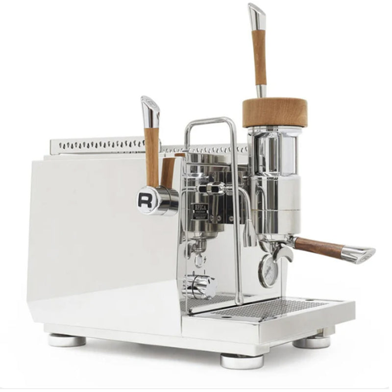 The Rocket Epica Lever Espresso Machine RE091N3N11, crafted by Rocket, features a sleek silver design with wooden handles. It includes a steam wand on the left and a manual brewing lever on the right. Utilizing advanced coffee technology, it boasts a minimalist polished metal finish along with a small platform at the base for placing cups.