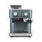 A sleek KitchenAid Semi Automatic Espresso Machine with Burr Grinder in juniper (KES6551JP). It features a teal blue-green color with a silver base, various buttons, knobs, and dials for settings, a coffee bean hopper on top, and a portafilter and steam wand at the front. The integrated Burr Grinder ensures precise grounds for your perfect brew.