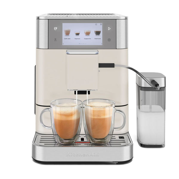 A sleek, modern KitchenAid KF8 Fully Automatic Espresso Machine (Porcelain) KES8558PL is brewing two barista-quality lattes simultaneously. This automatic espresso machine from KitchenAid features a digital display and has a milk frothing container conveniently attached on the right side. Both lattes are served in clear glass cups, beautifully showcasing their layers of espresso and milk.