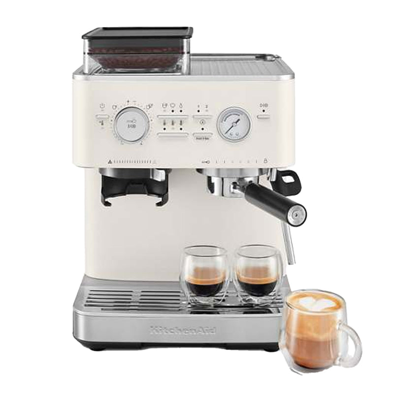 KitchenAid Semi Automatic Espresso Machine with Burr Grinder KES65SPL (Porcelain) by KitchenAid features a built-in burr grinder, pressure gauge, and steam wand. The machine is brewing two espresso shots side by side in transparent double-walled glasses. A separate glass cup with latte art is placed beside the machine.