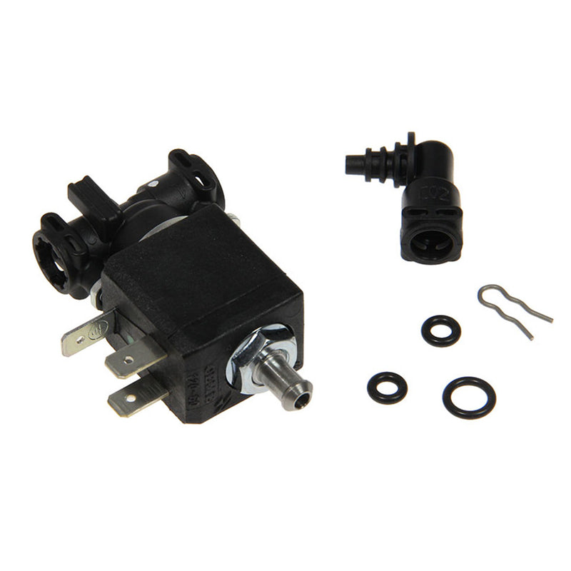 The image displays the Delonghi Parts: Solenoid Valve (3VA 120V): 5513225801 by DeLonghi. The main Magnifica solenoid valve, featuring metal prong connectors and a cylindrical metal pipe fitting, is accompanied by various components including O-rings, a plastic elbow connector, and a metal clip.