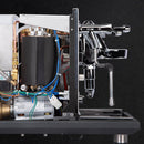 A close-up of a partially disassembled ECM Synchronika II espresso machine by ECM showcases its dual boiler, internal components like wires, motor, and boiler. The chrome steam wand and group head are highlighted on the right against a black background, emphasizing its rapid heat-up technology.