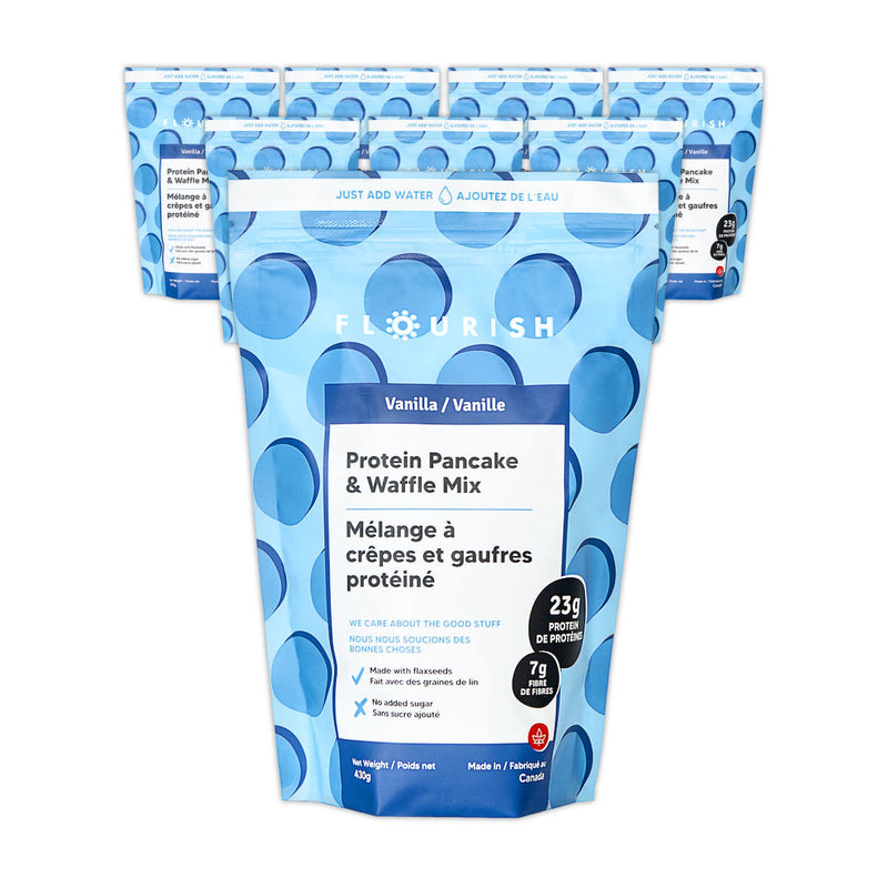 Image of multiple standing pouches from the Flourish Vanilla Protein Pancake & Waffle Mix (Case of 8). The blue pouches feature non-GMO ingredients and highlight nutritional details such as 23g of protein and 7g of fiber per serving. Instructions are provided in both English and French, stating "Just Add Water.