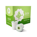 A bright green box labeled "My Little Brew Natural Decaf Single-Serve Coffee Pods (Box of 24)" features a charming cartoon water droplet character holding a coffee cup. In front of the box, there are two white pods, one partially lying down. The clean design is set against a pristine white background.