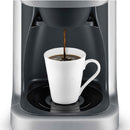 A sleek Breville Grind Control™ Stainless Steel Thermal Coffee Maker BDC650BSS with a silver, metallic finish dispenses rich, dark coffee into a white ceramic mug on its drip tray. Utilizing Steep and Release technology, the machine ensures optimal flavor extraction, while the mug sits perfectly centered under the dispenser.